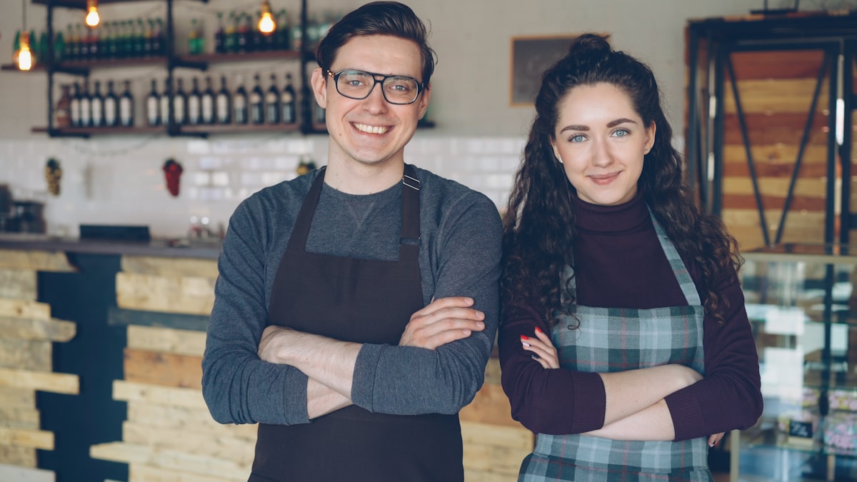 Two small business owners smiling in their shop